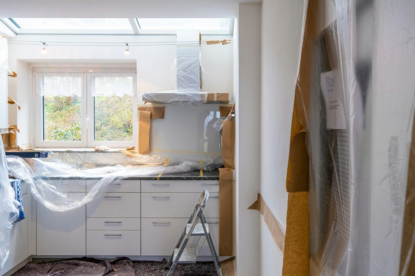 Kitchen mid-renovation with cabinets wrapped in protective paper